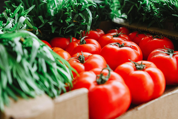 Tomatoes and greens on a table in a box